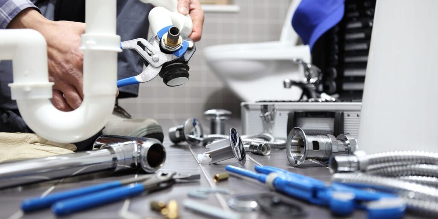 Plumber working with pipes and tools in a bathroom